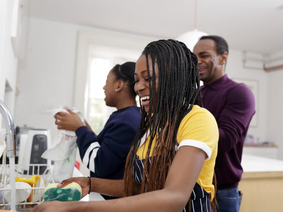 Two teenage girls and Dad having fun while washing up in the home